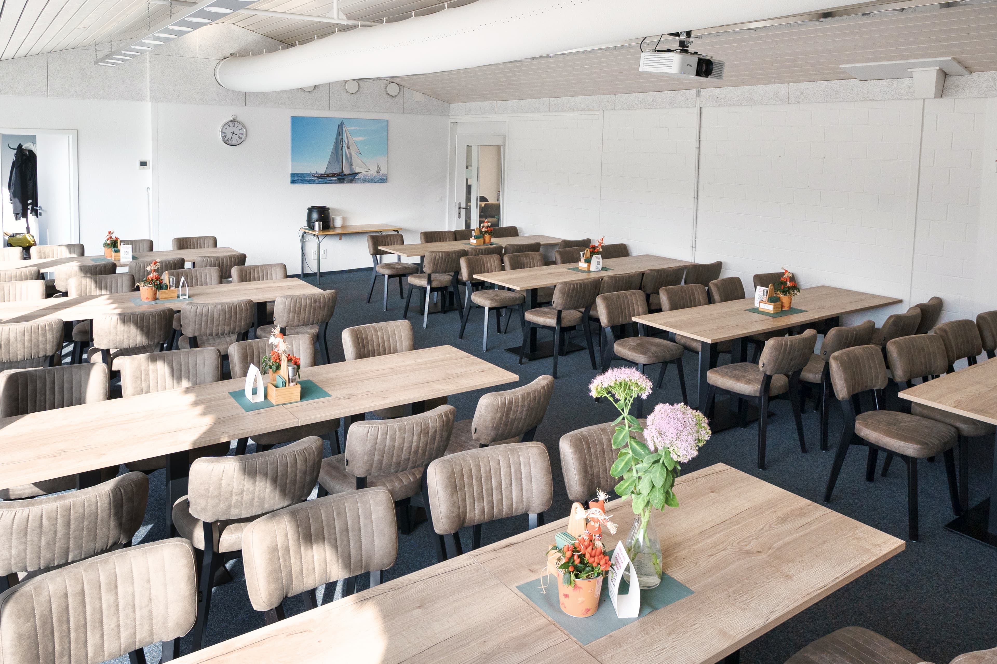 Speisesaal mit Holztischen und Polsterstühlen sowie Edelstahl-Theke bei AIP Plus in Pratteln – Bild 1